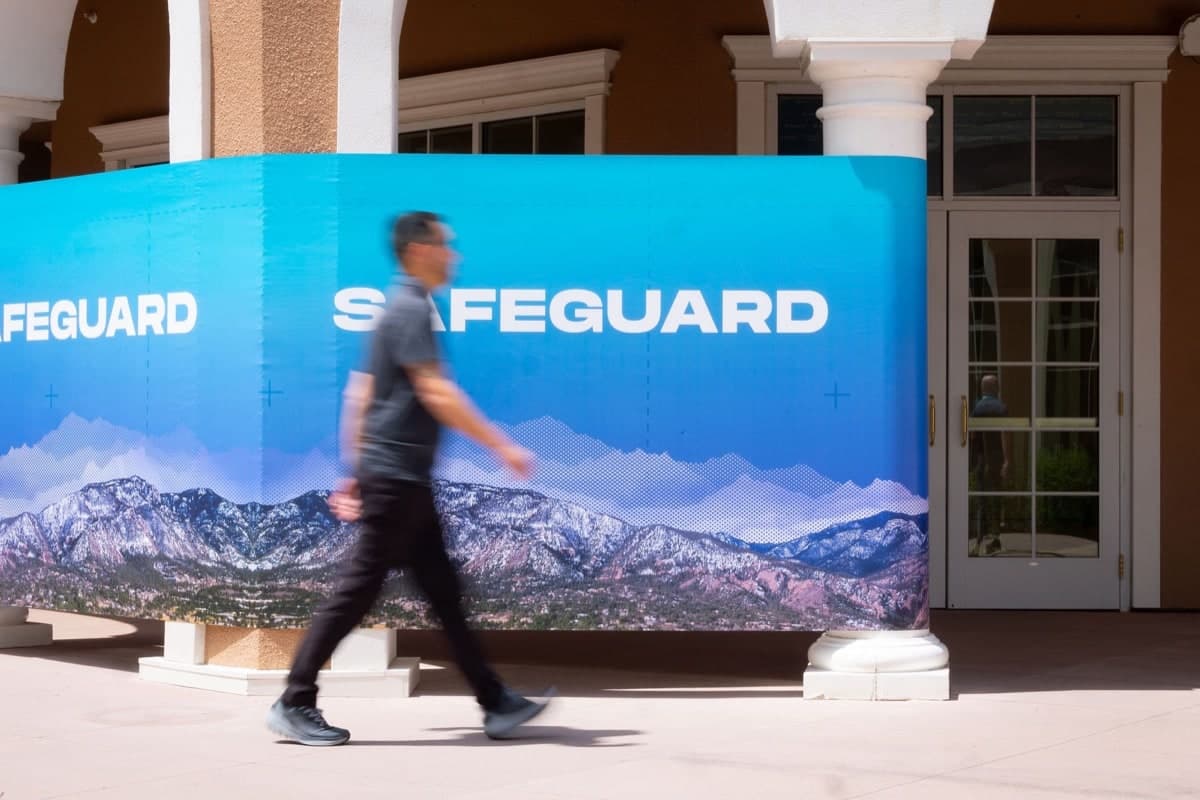 A Safeguard backdrop on the resort portico, an attendee passing mid-stride